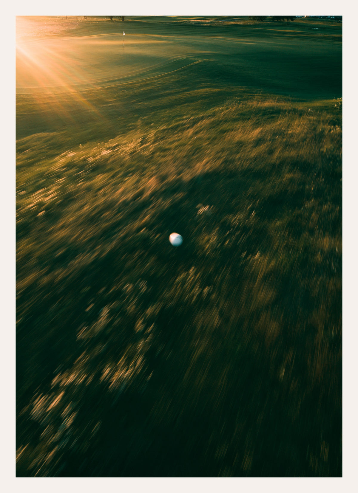 Kunstdruck: Golfball im Morgenlicht über einem Fairway, weiches Gegenlicht